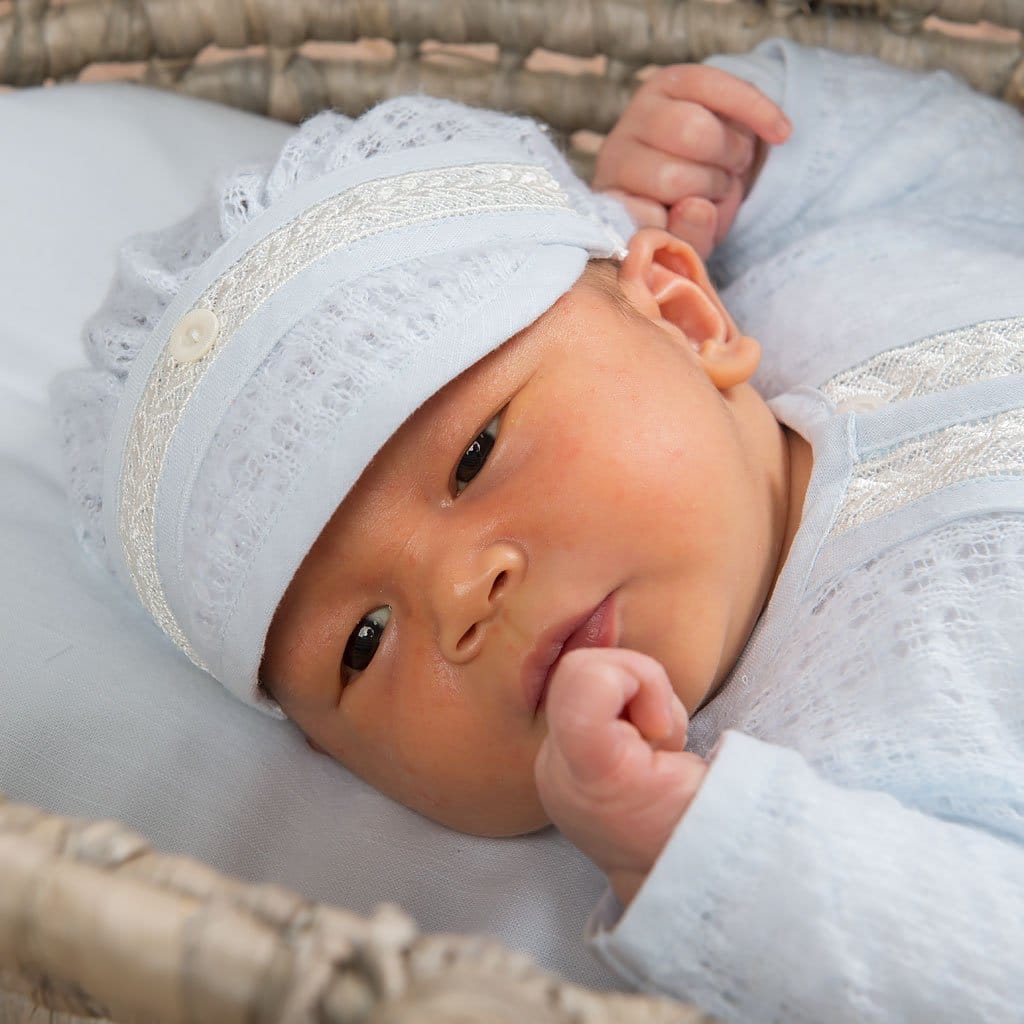Another view of a baby in the Harrison Newborn Sweater, highlighting the elegant texture and delicate trim.