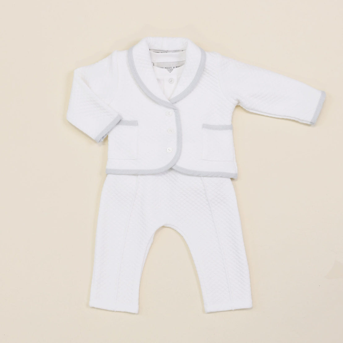 A flat lay of the Harrison Quilted Newborn Suit, featuring the quilted jacket over the matching pants and bodysuit with delicate details.