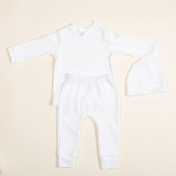 Introducing the Ivory Pima Top & Leggings set, a handcrafted baby outfit from the USA. This ensemble, featuring a long-sleeved top, matching leggings, and a cozy hat is crafted from soft Pima cotton. Arranged on a light background, it presents a simple yet elegant minimalist design.