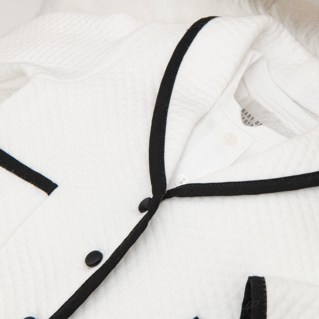 Detail of the white quilted jacket from the James 3-Piece Suit, highlighting the black trim and buttons.