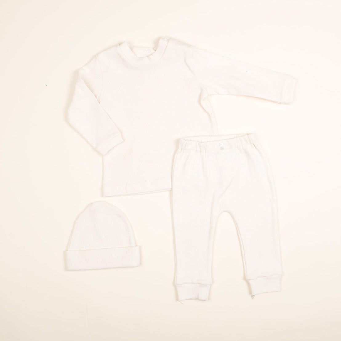 This charming Natural Ivory Ribbed Cotton Top & Leggings set, handmade in the USA, includes a long-sleeve top and leggings. Crafted from soft ribbed textured cotton, it ensures comfort for your little one.
