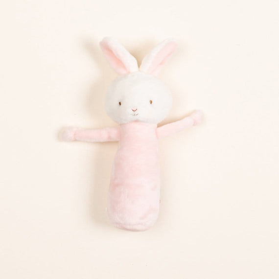 A flat lay photo of a Pink Bunny Baby Rattle against a cream backdrop.