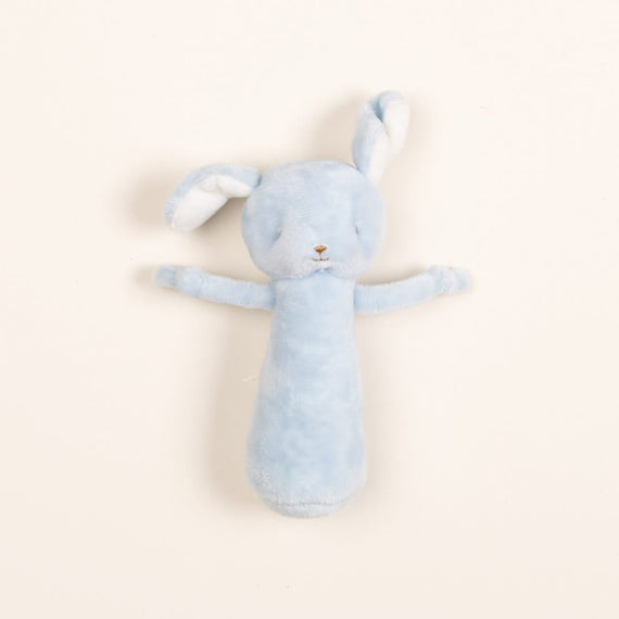 Upscale soft blue Puppy Chime Rattle with long ears and arms, lying flat on a vintage light beige background.