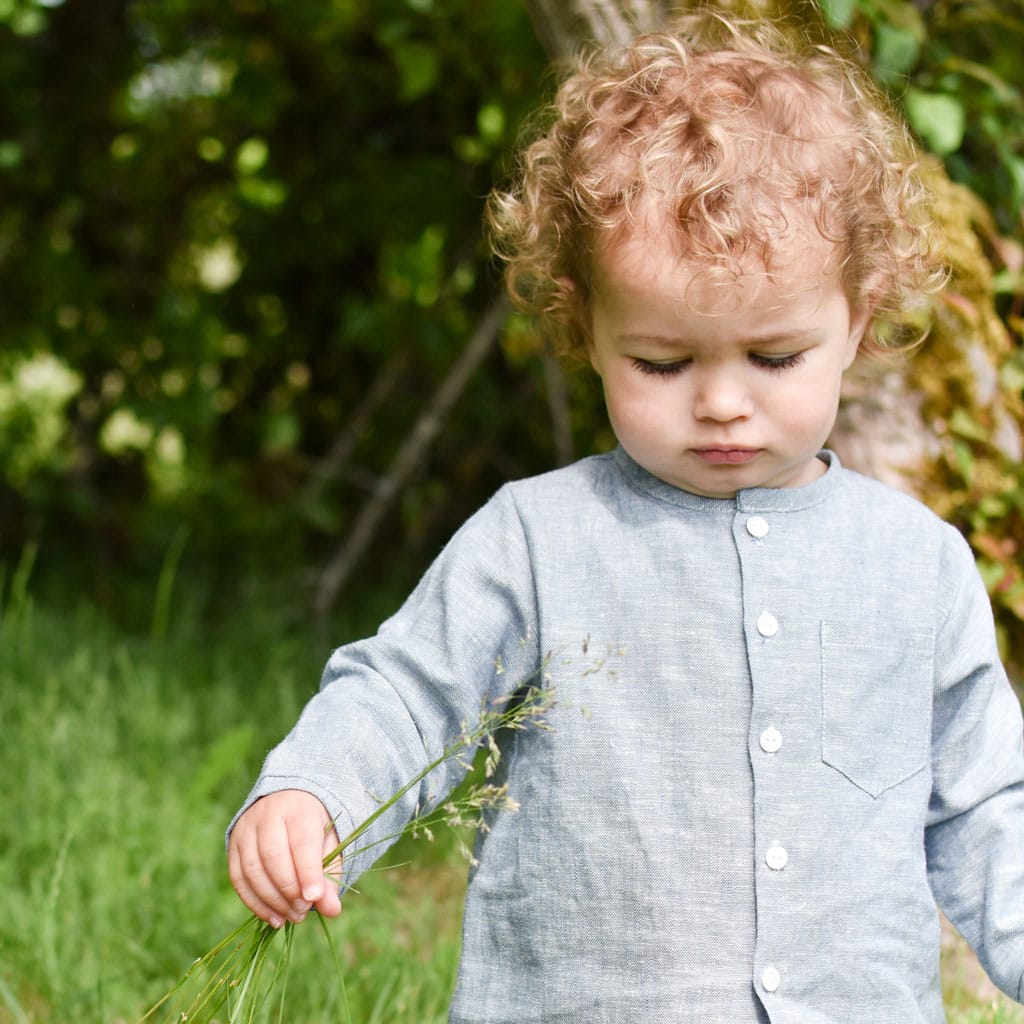 Photo of a baby boy outside in the forest wearing the Silas Linen Shirt in indigo
