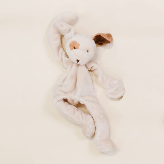 A soft, plush toy rabbit with floppy ears, one ear brown and the other white, on a light beige background. The Baby Beau & Belle Silly Puppy Buddy pacifier holder is lying flat, facing upwards.