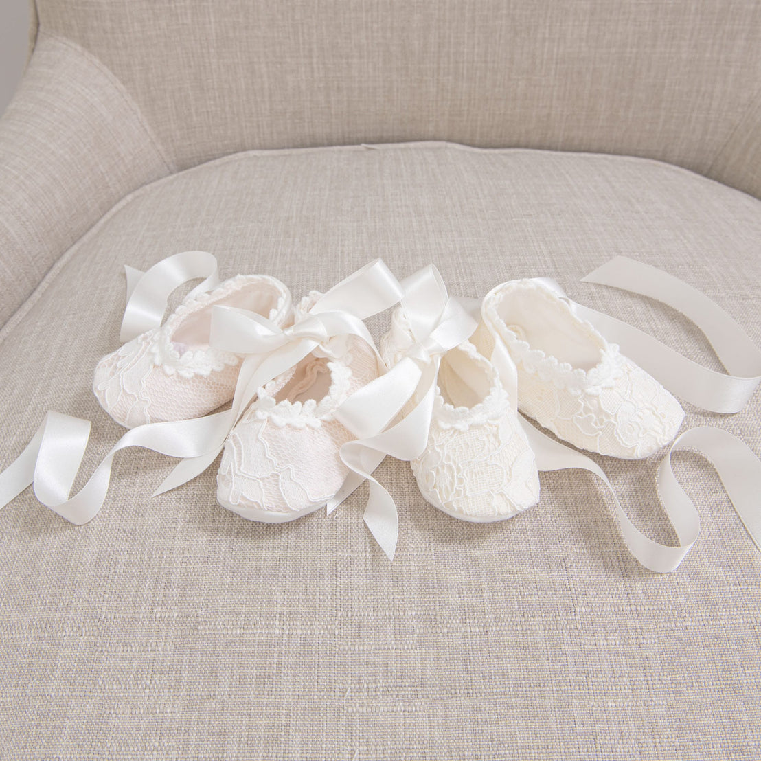 Closeup photograph of two baby booties. One in pink and the other in Ivory. 